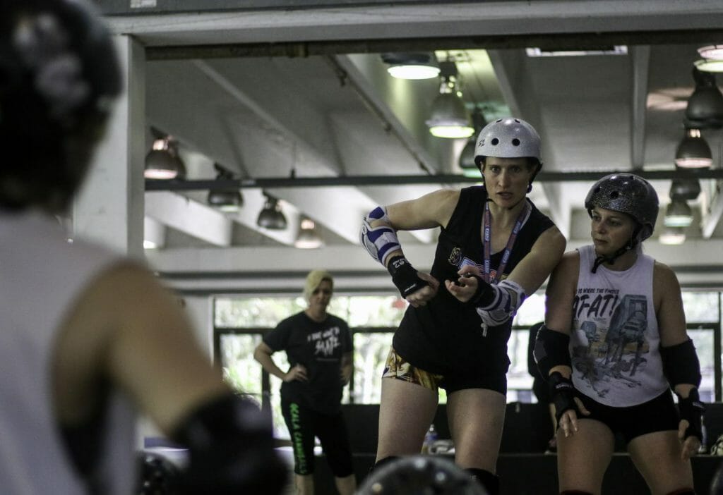 Hillary Buscovick, a 31-year-old professional roller derby skater, works with Lizz Zieschang, 28, to demonstrate blocking techniques at a workshop for local skaters at the Alachua County Fairgrounds on Saturday